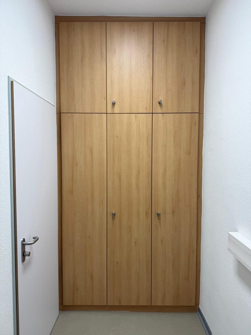 Wandschrank aus Holz mit geschlossenen Türen, passgenau bis unter die Decke eingebaut