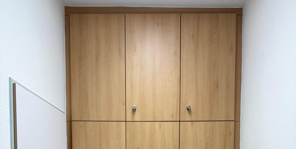 Wandschrank aus Holz mit geschlossenen Türen, passgenau bis unter die Decke eingebaut