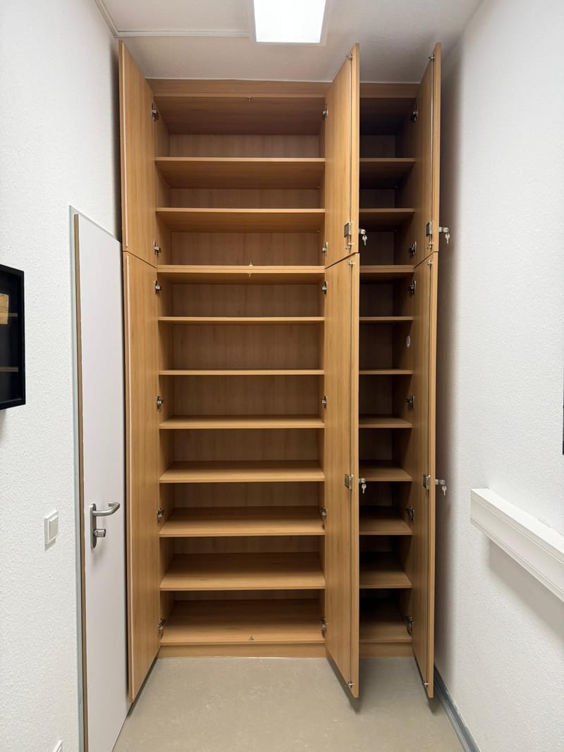 Der geöffnete Wandschrank zeigt zahlreiche Regalfächer für maximalen Stauraum